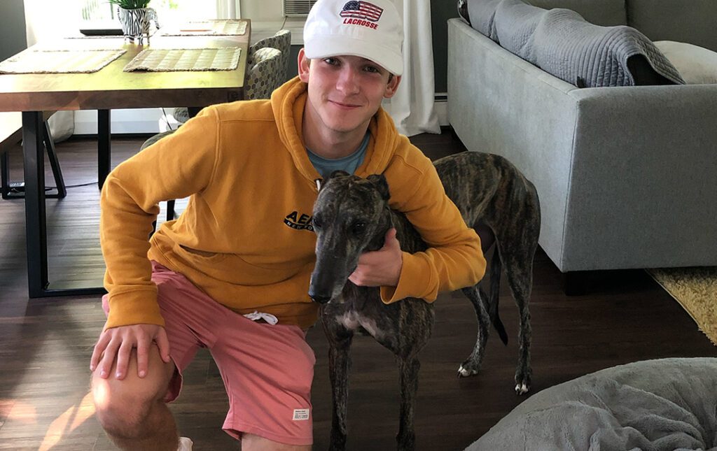 a teenager hugging a greyhound